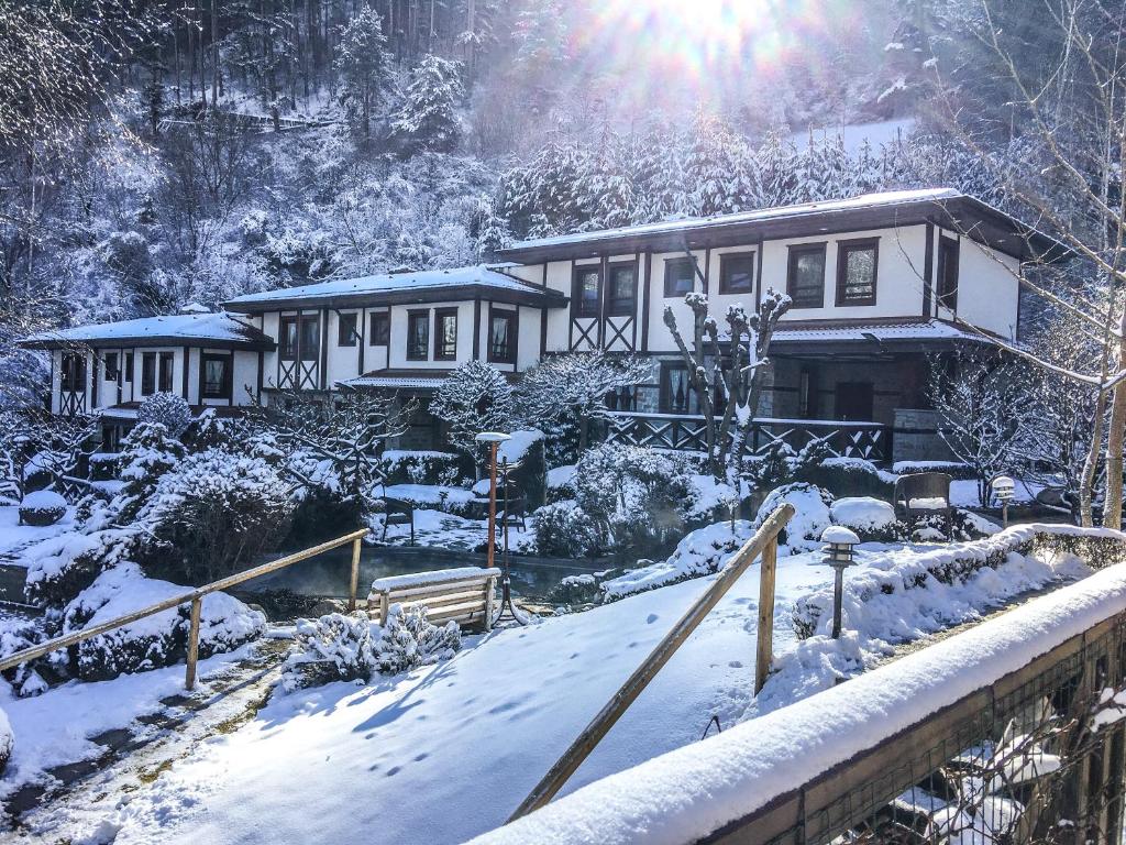 a house covered in snow with the sun behind it at Spa Hotel Ismena in Devin