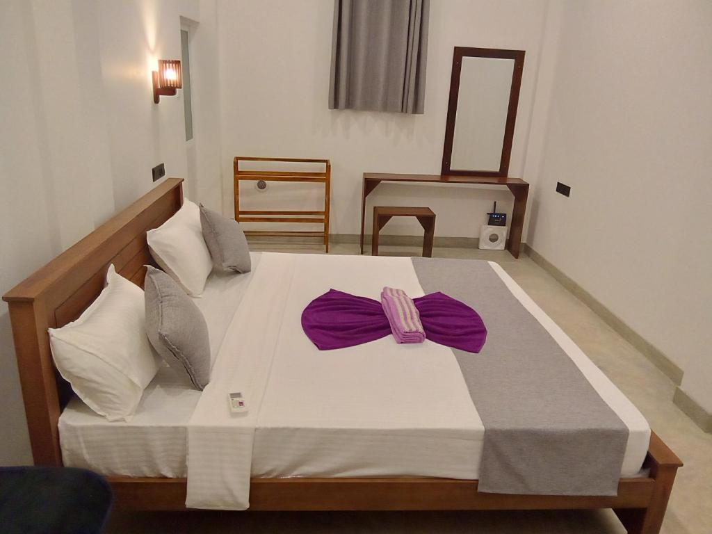 una camera da letto con un letto con un fiocco viola sopra di LaRoy Mirissa-Introducing Smart Hotel a Mirissa