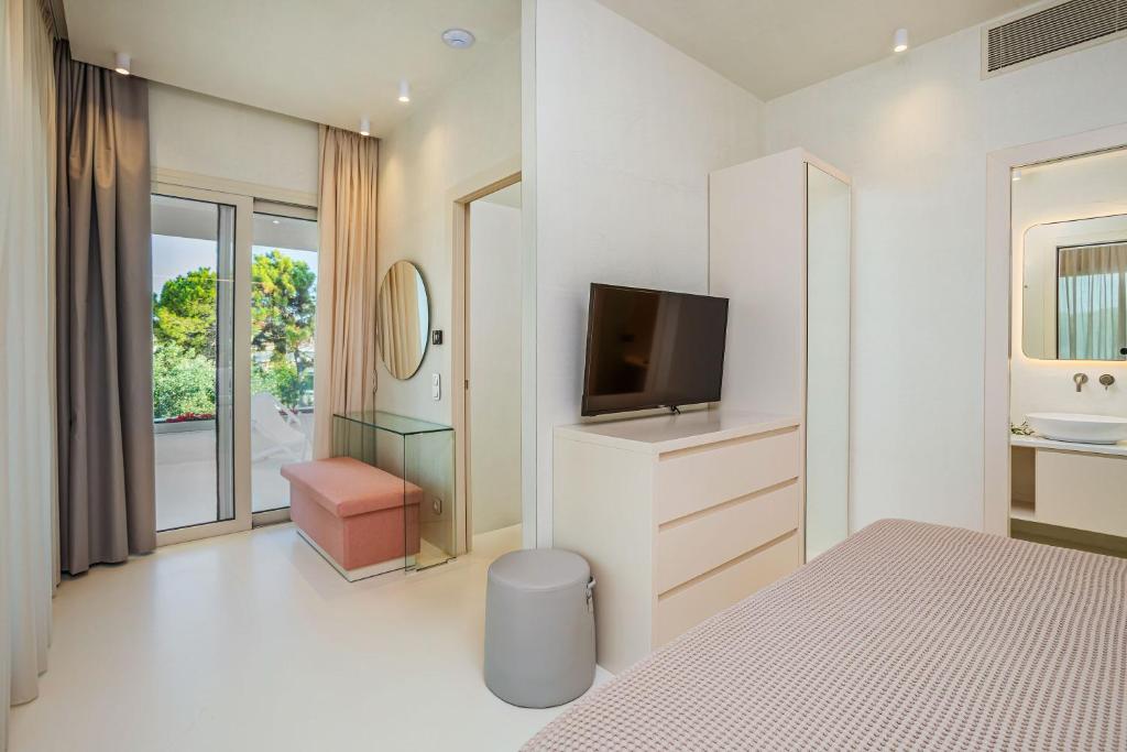 a white bedroom with a tv and a bed at Cocoοns Suites & Villas Fourka in Fourka