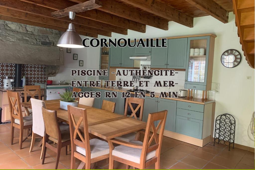 een eetkamer met een houten tafel en stoelen bij Cornouaille / Domaine la Blanche Hermine in Plounérin