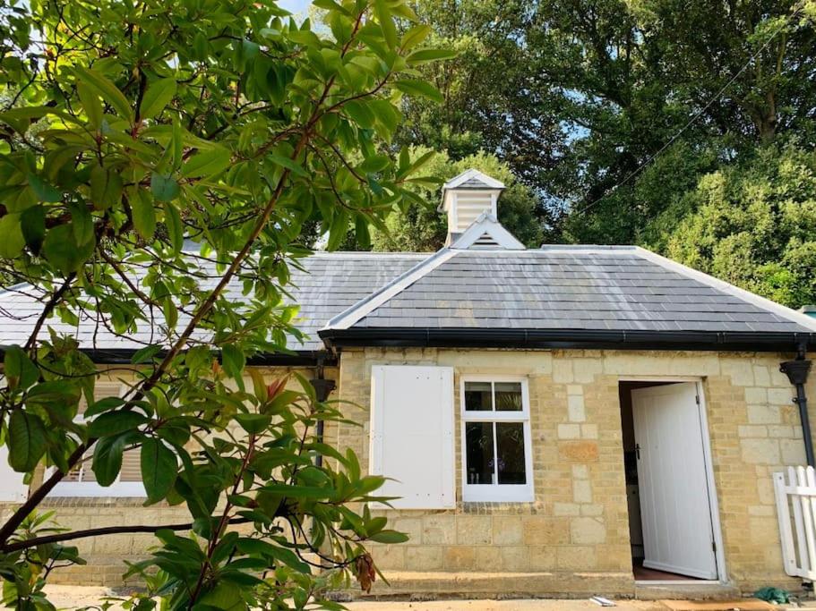 a small brick house with a white door and a window at Smugglers Lodge at Ventnor Botanic Garden in Ventnor