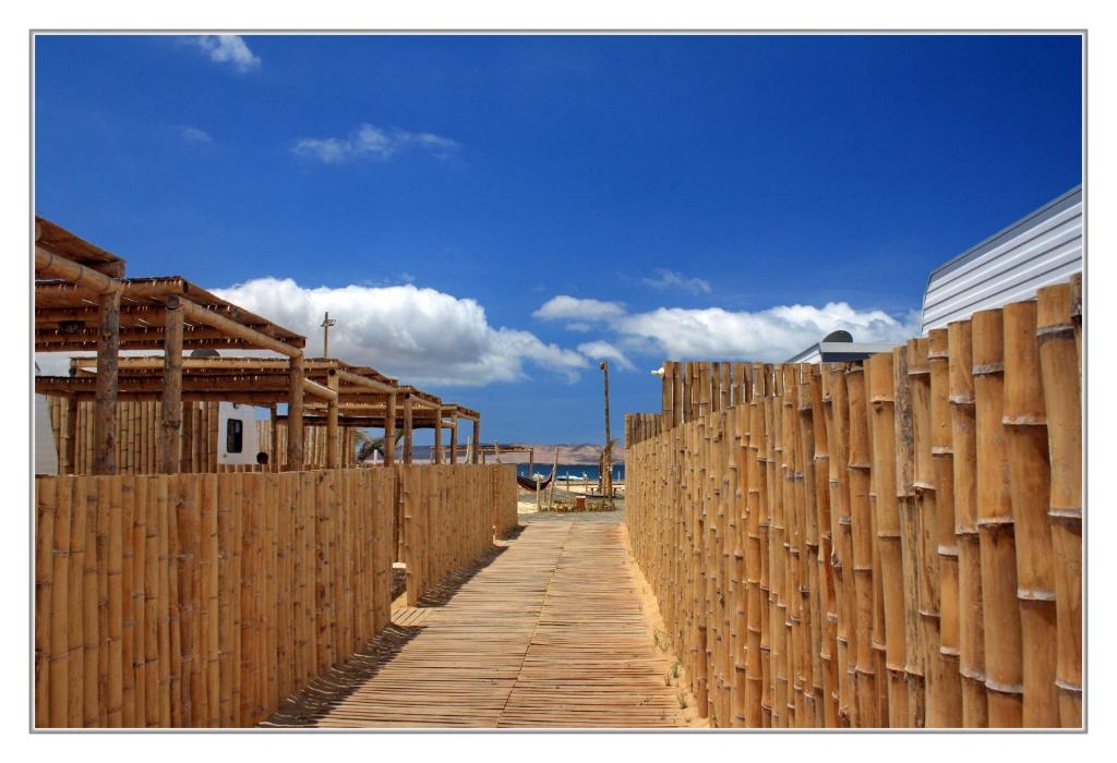 een houten hek naast een houten loopbrug bij Bamboo Paracas Resort in Paracas