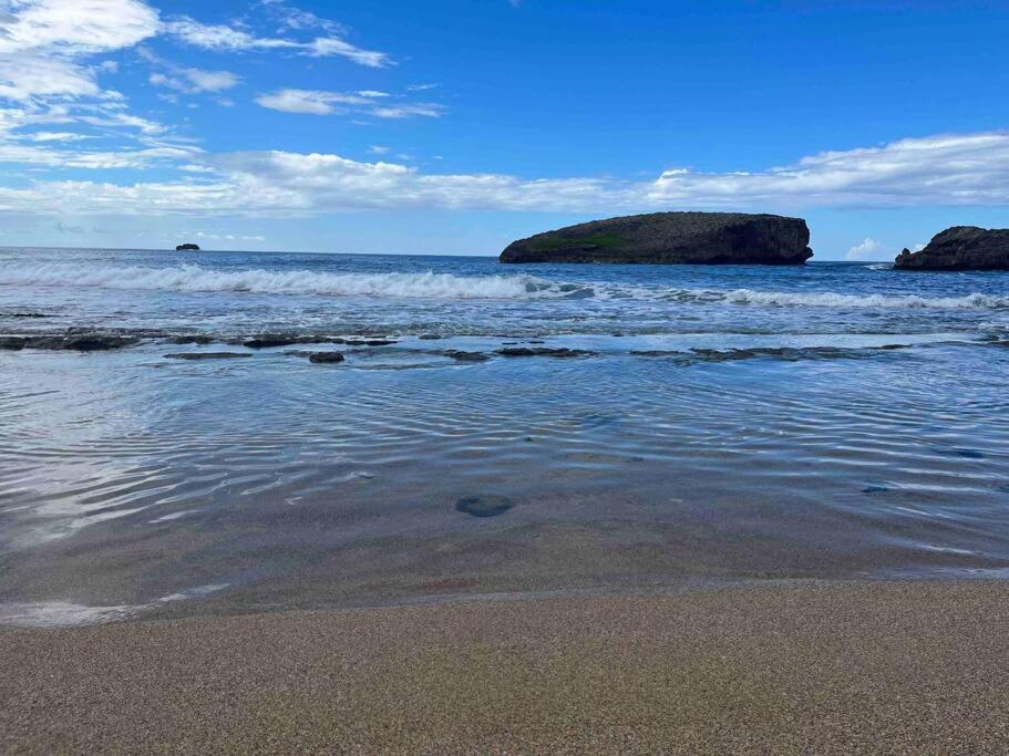 a beach with two large rocks in the water at Huellas in Arecibo