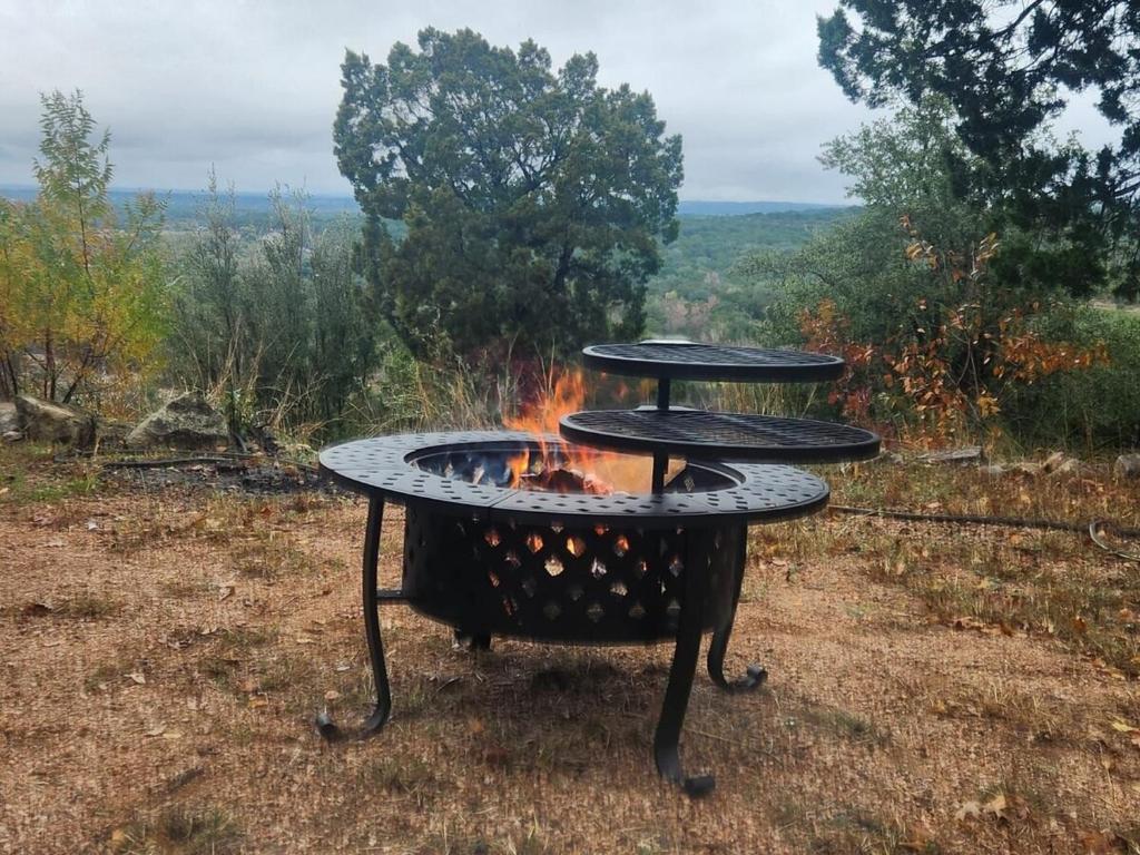 a barbecue grill with a fire in a field at Entire 2br 2ba hilltop view home Sleeps 8 pets 4 acres Jacuzzi Central AC Kingbeds Free Wifi-Parking Kitchen WasherDryer Starry Terrace Two Sunset Dining Patios Grill Stovetop Oven Fridge OnsiteWoodedHiking Wildlife CoveredPatio4pets & Birds Singing! in Marble Falls