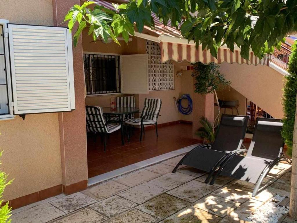 a house with a patio with chairs and a table at Private Garden in Novamar 5 in Puerto Marino