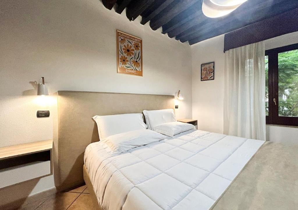 Un dormitorio con una gran cama blanca y una ventana en Sardinia Domus, en Cagliari