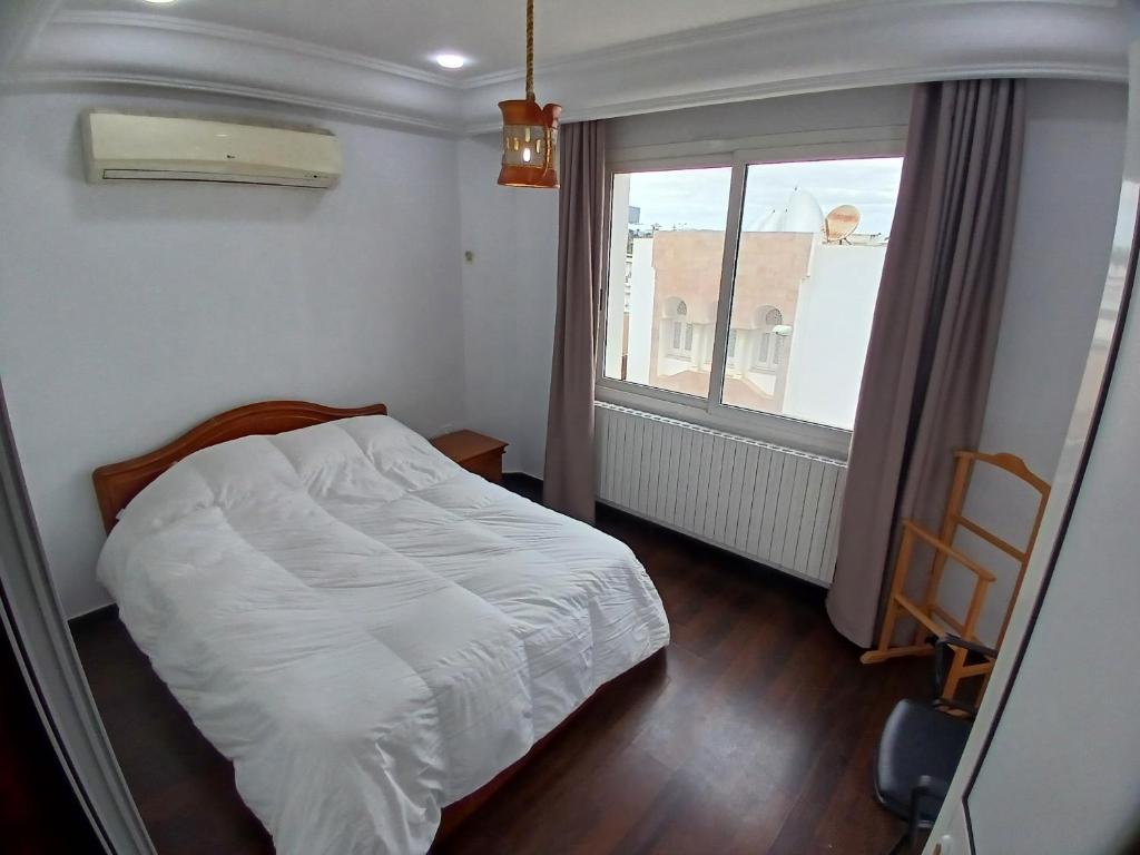 ein kleines Schlafzimmer mit einem Bett und einem Fenster in der Unterkunft Sunny Inn Les berges du lac 1 in Tunis