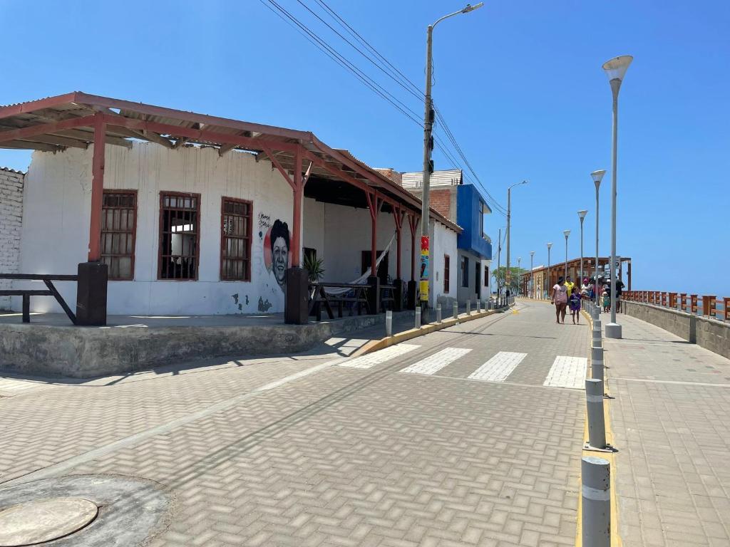 Eine Straße mit einem Gebäude und Menschen gehen eine Straße hinunter in der Unterkunft Casa de mamá María in Malabrigo