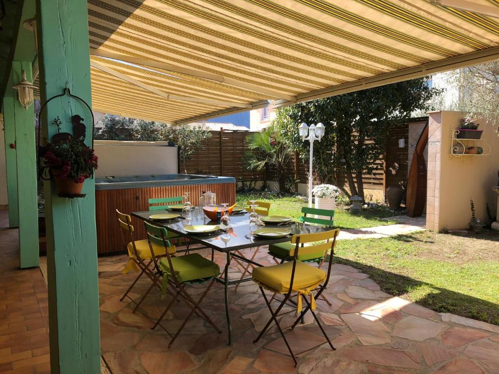 un patio avec une table et des chaises sous une pergola dans l'établissement proche de Collioure maison au calme avec Spa, à Saint-André
