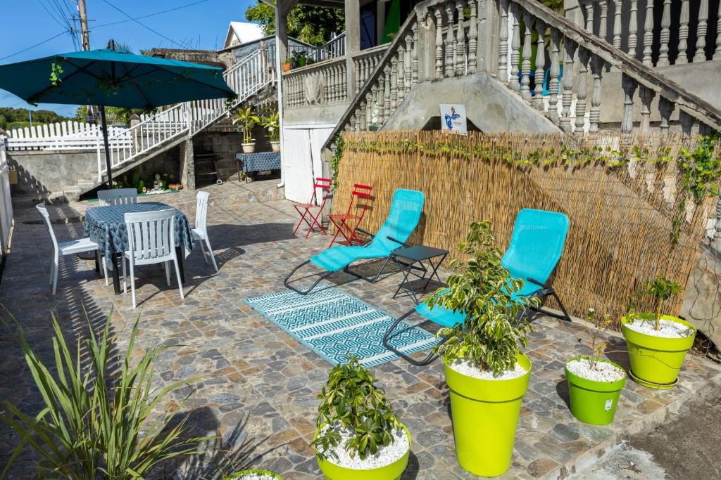 patio z krzesłami, roślinami i parasolem w obiekcie La villa du soleil 971 w mieście Anse-Bertrand