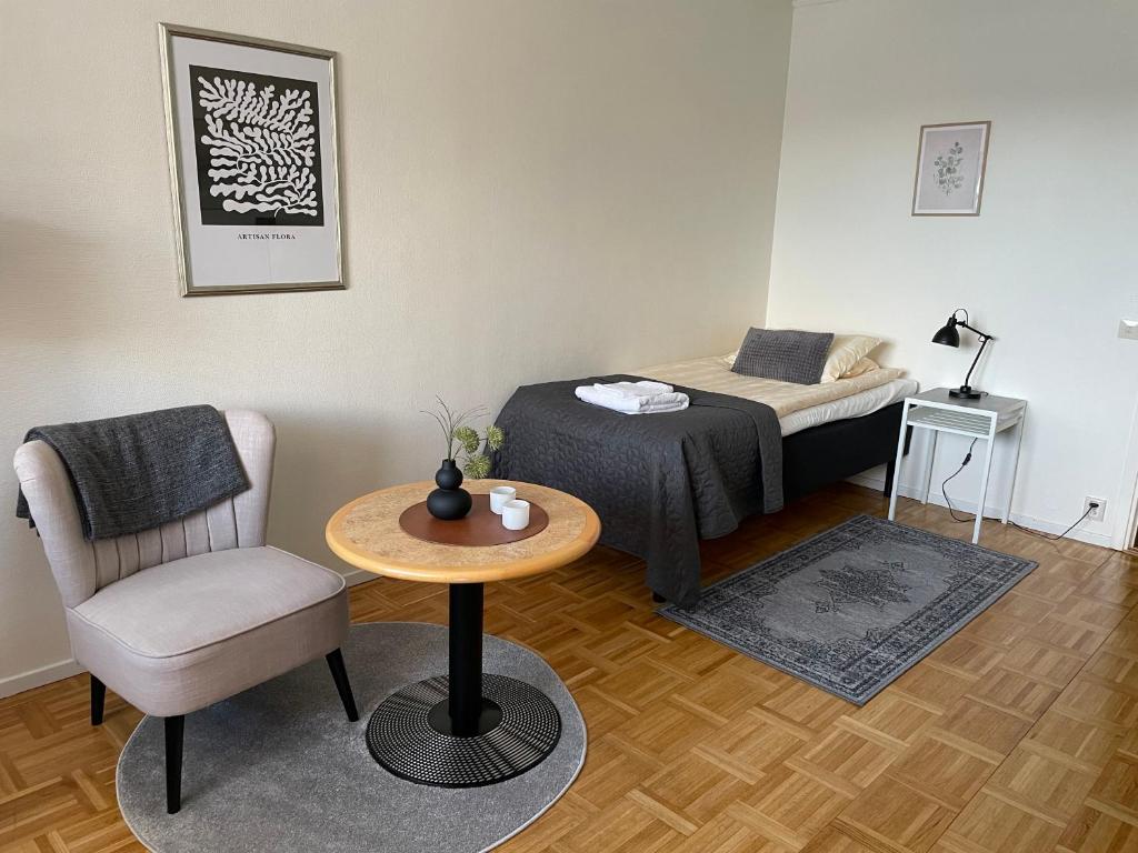 シェブデにあるRS Lägenhetshotell Skövdeのベッド、テーブル、椅子が備わる小さな客室です。