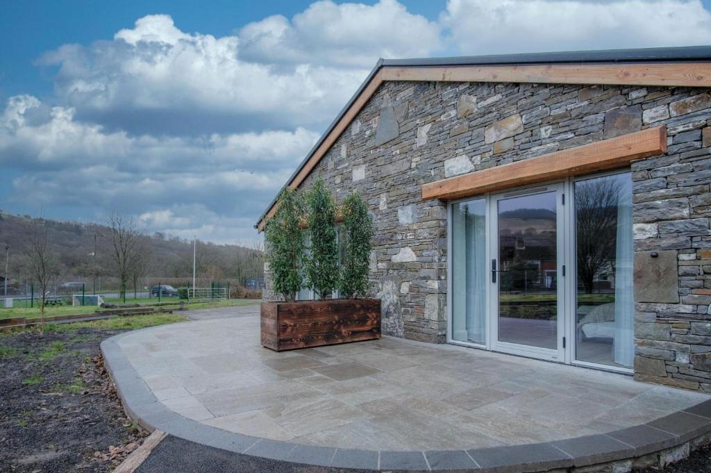 a stone building with a patio with a plant on it at Suite 6 - Sleeping Giant Hotel - Pen Y Cae Inn in Brecon