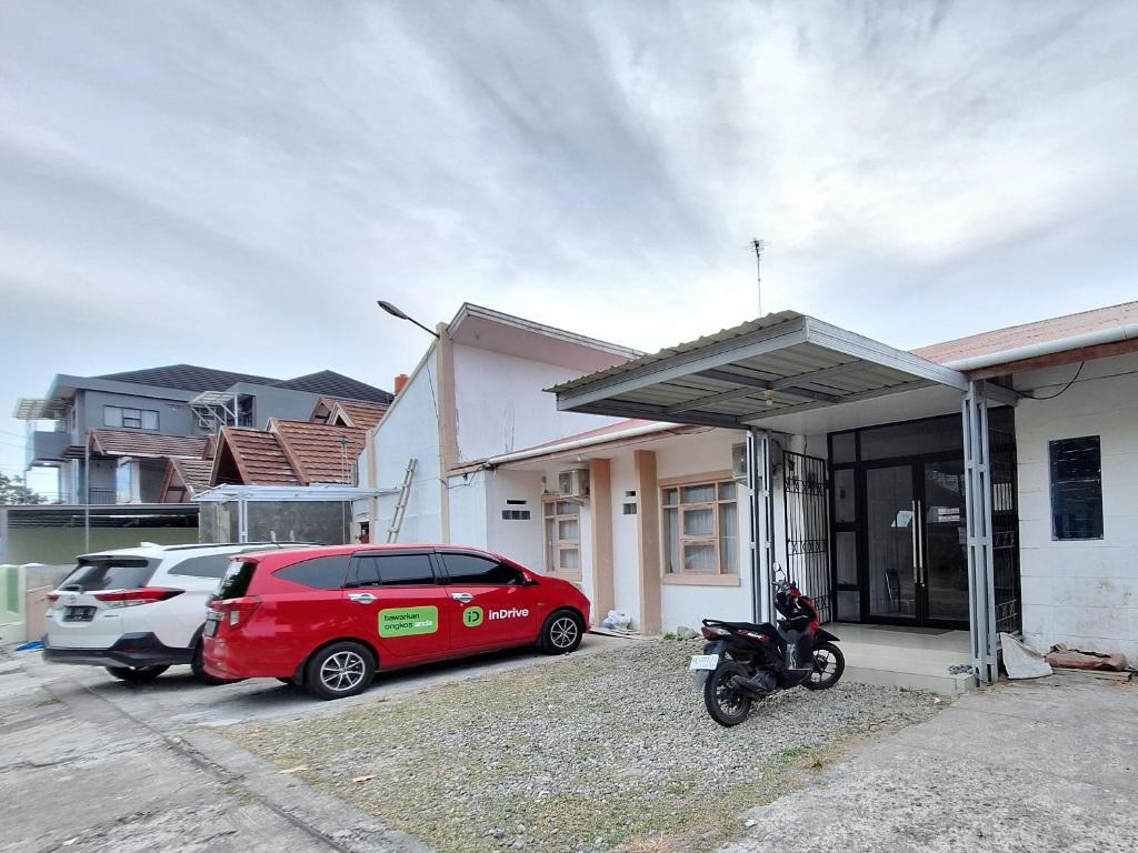 a red car parked in front of a house at Tanjung Syariah in Padang