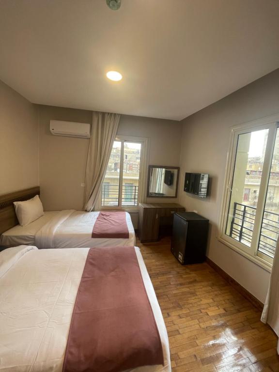 a hotel room with two beds and a television at New Lotus Hotel in Cairo