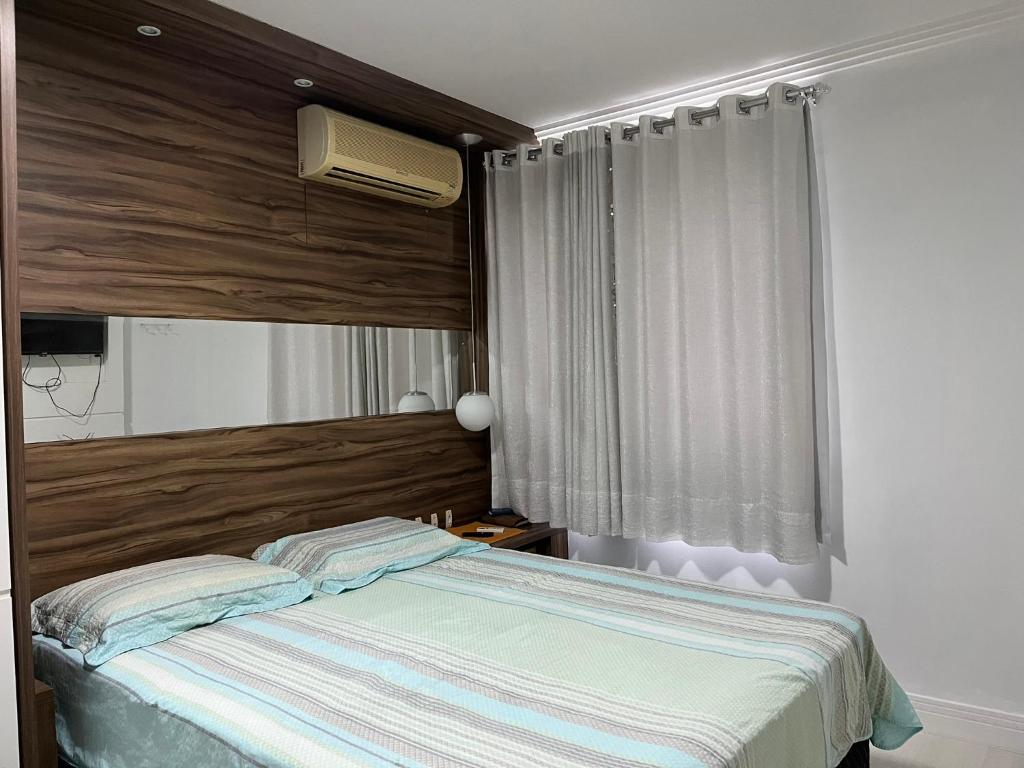 a bedroom with a bed and a window at Suítes e quartos no Centro de Blumenau in Blumenau