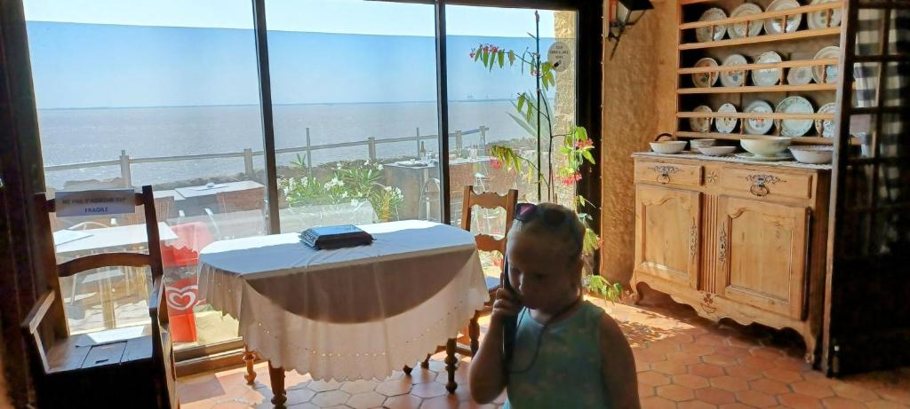 a small child standing in a room with a table at Les Charmettes - SIBLU in Les Mathes