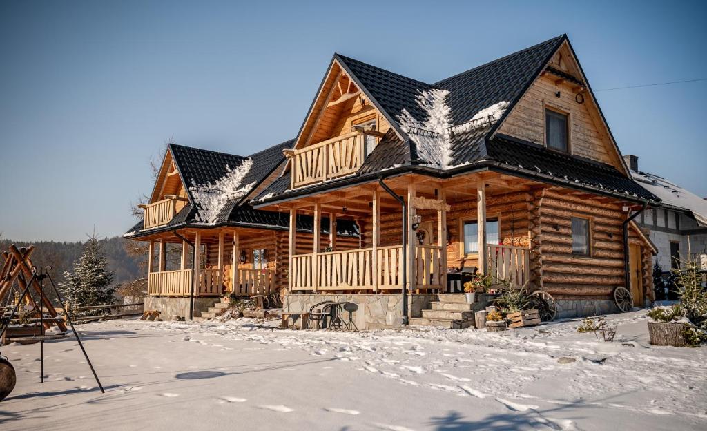 duży drewniany dom z śniegiem na ziemi w obiekcie HRYCÓWKA Domki z Widokiem w mieście Grywałd