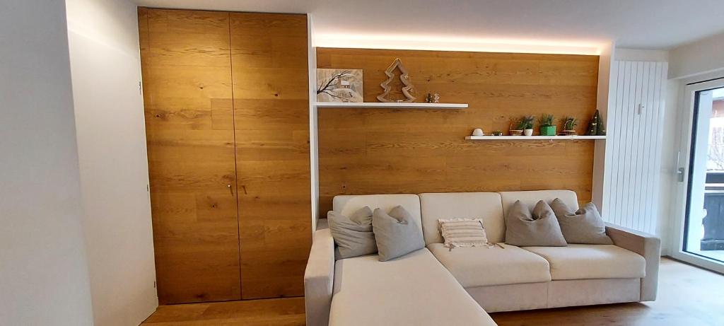 - un salon avec un canapé et un mur en bois dans l'établissement Relax Home Fie' allo Sciliar - Alpe di Siusi Val Gardena, à Fiè