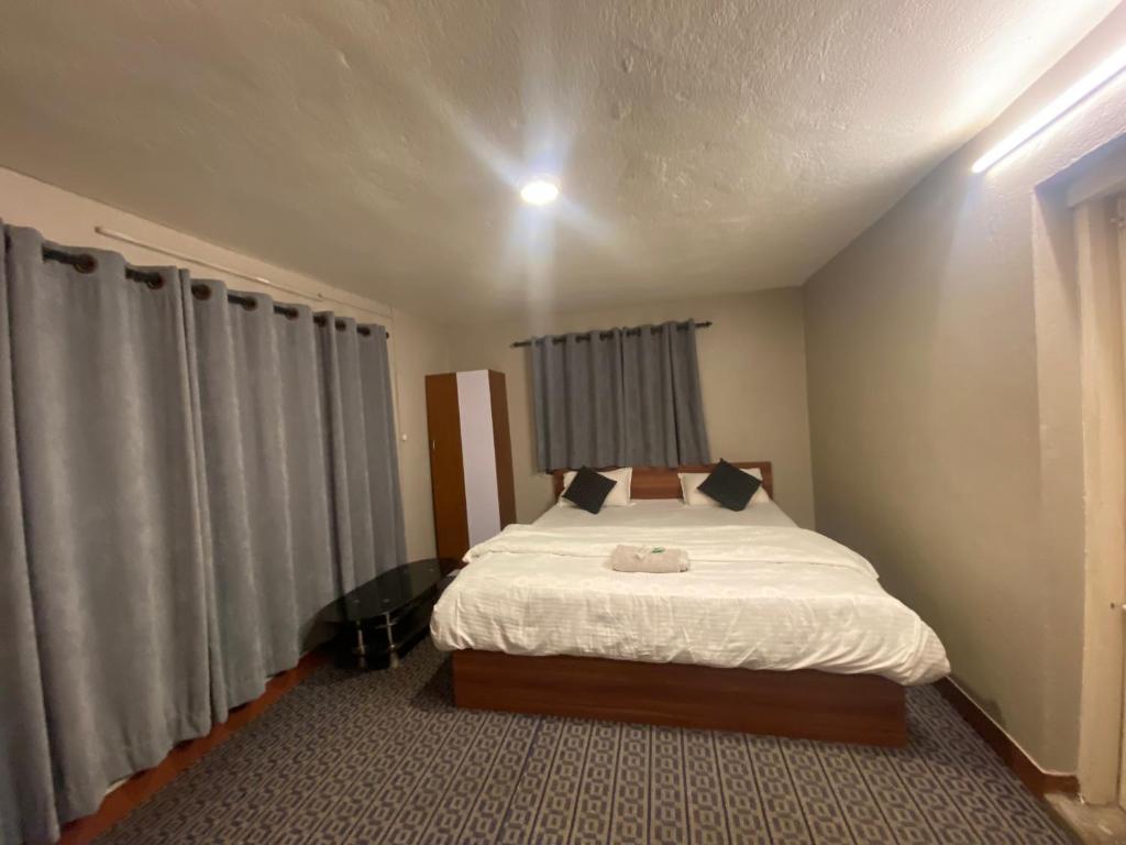 a small bedroom with a bed with white sheets at Pork Hub in Pātan