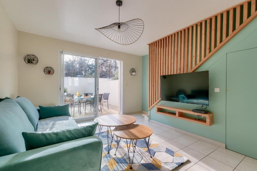 un salon avec un canapé bleu et une télévision dans l'établissement Maison moderne et piscine commune, à Les Sables-dʼOlonne