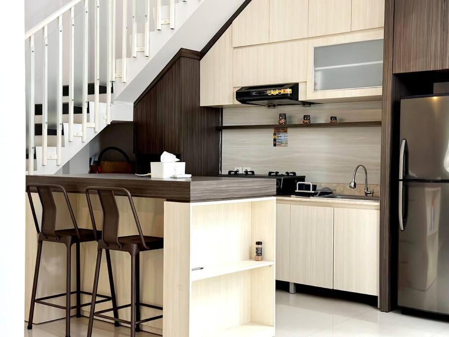 a kitchen with a counter with stools and a refrigerator at Villa Blue Saphire Sanur Mansion Bali in Denpasar