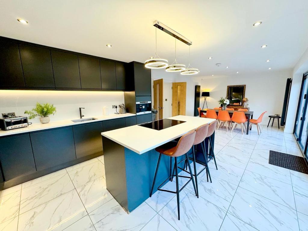 a kitchen with a island with stools at Luxury 7 Bedroom House in Didsbury, Manchester in Manchester