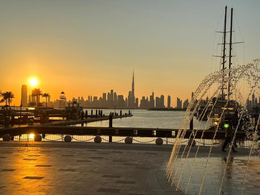 a view of the city at sunset with a boat at Creek Harbour retreat: Luxurious 2-BR apartment in Dubai