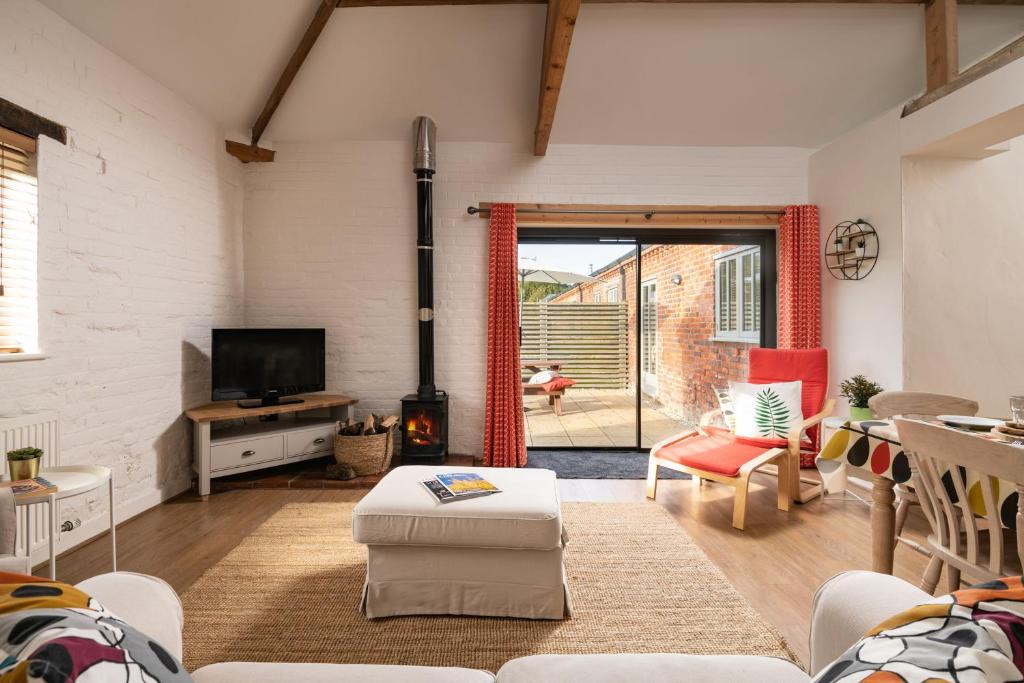 sala de estar con sofá, TV y chimenea en Wagtail, en Fakenham