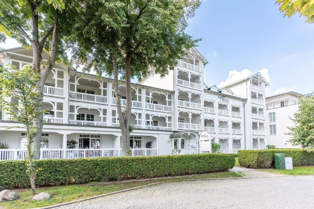 Un gran edificio blanco con árboles delante. en Ferienwohnung 8 Aparthotel Binz, en Binz