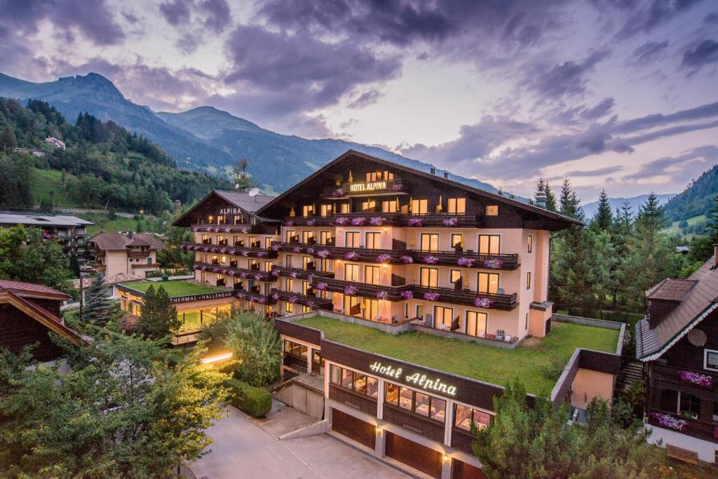 un gran edificio con montañas en el fondo en Hotel Alpina - Thermenhotels Gastein, en Bad Hofgastein