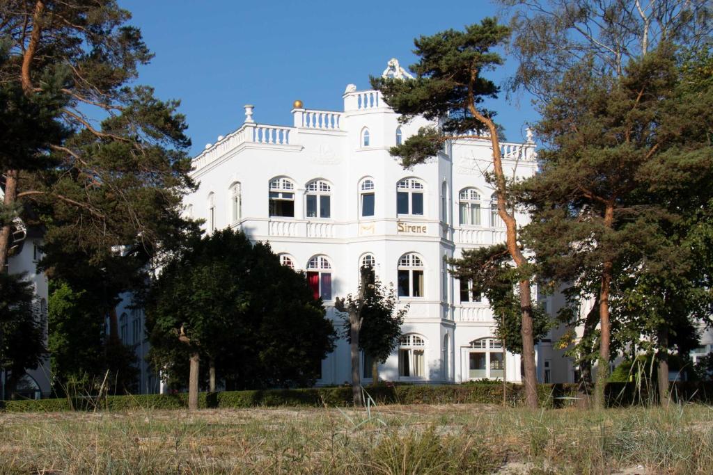 ein weißes Haus mit Bäumen davor in der Unterkunft Villa Sirene in Binz