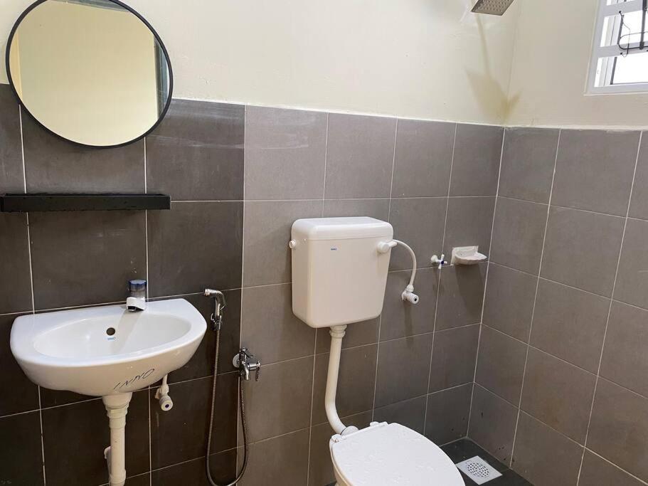 a bathroom with a sink and a toilet and a mirror at Rumah Aidin Homestay in Sitiawan