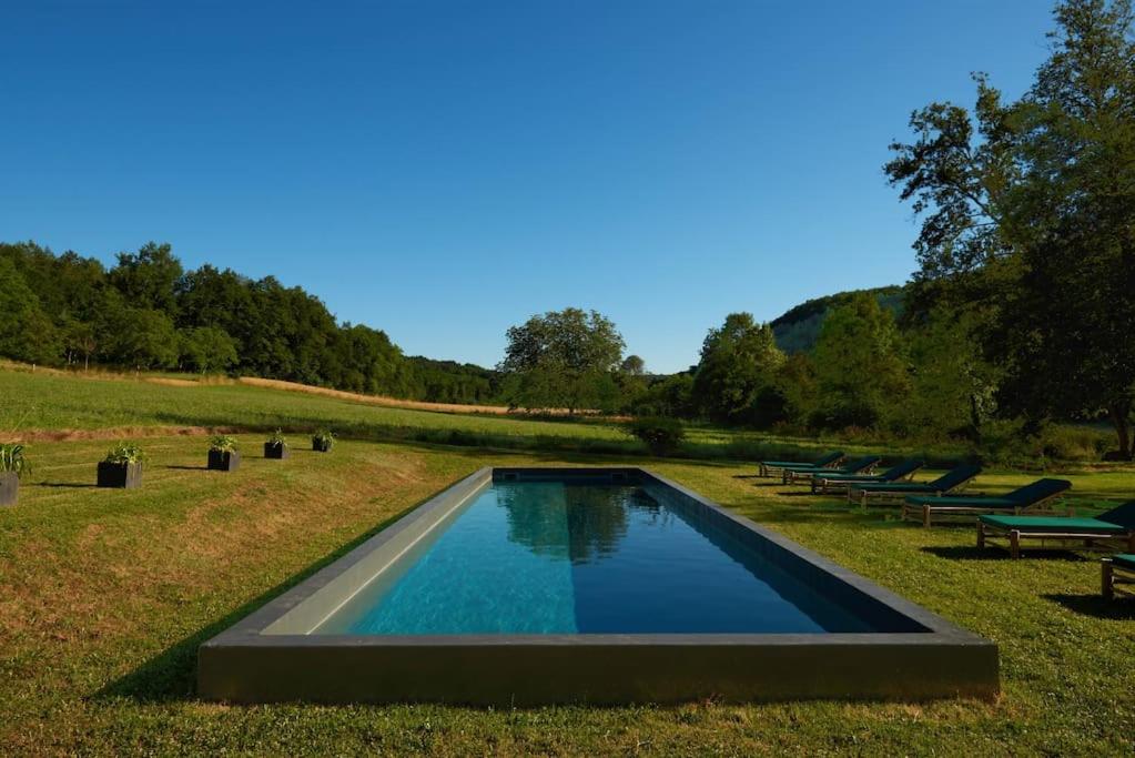 uma piscina no meio de um campo com bancos em Le Pressoir - domaine du Chateau de La Bourlie - Boutique villa up to 12 guests em Urval