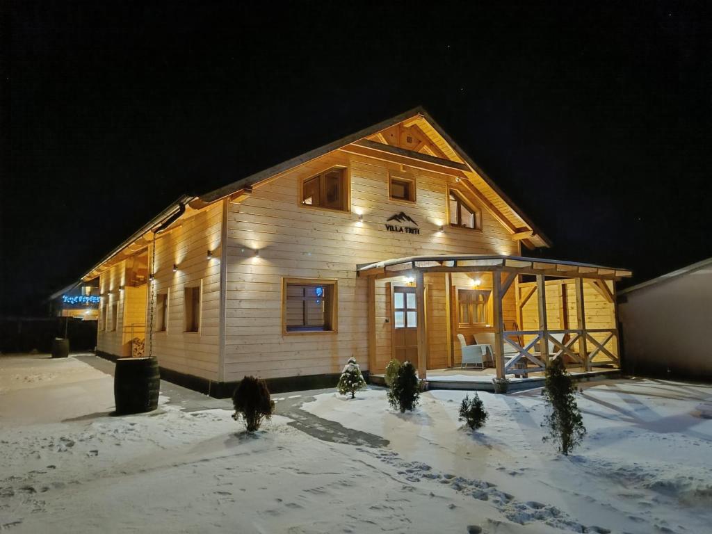 a wooden house in the snow at night at Villa Triti in Stará Lesná