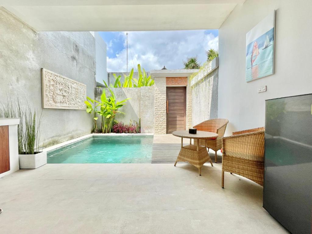a patio with a pool and a table and chairs at Livin Sanur Villa in Denpasar