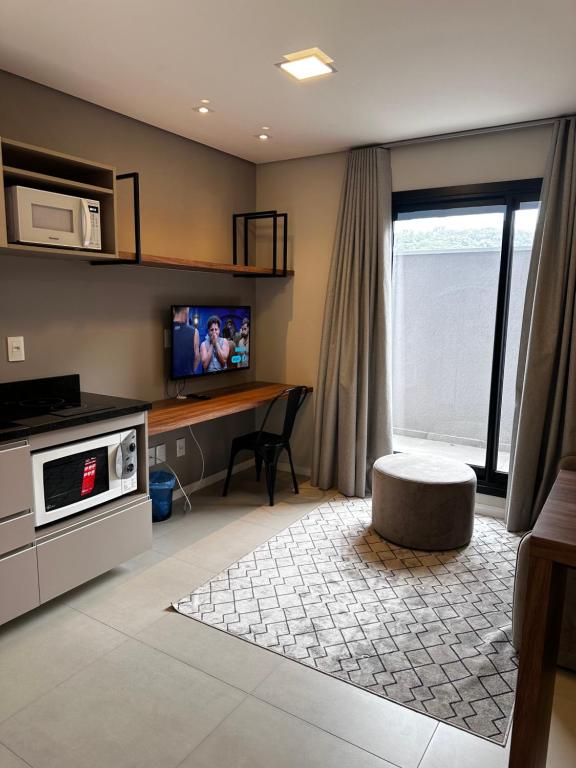 a living room with a television and a table with a microwave at STUDIO Perto da feevale campus 2 in Novo Hamburgo