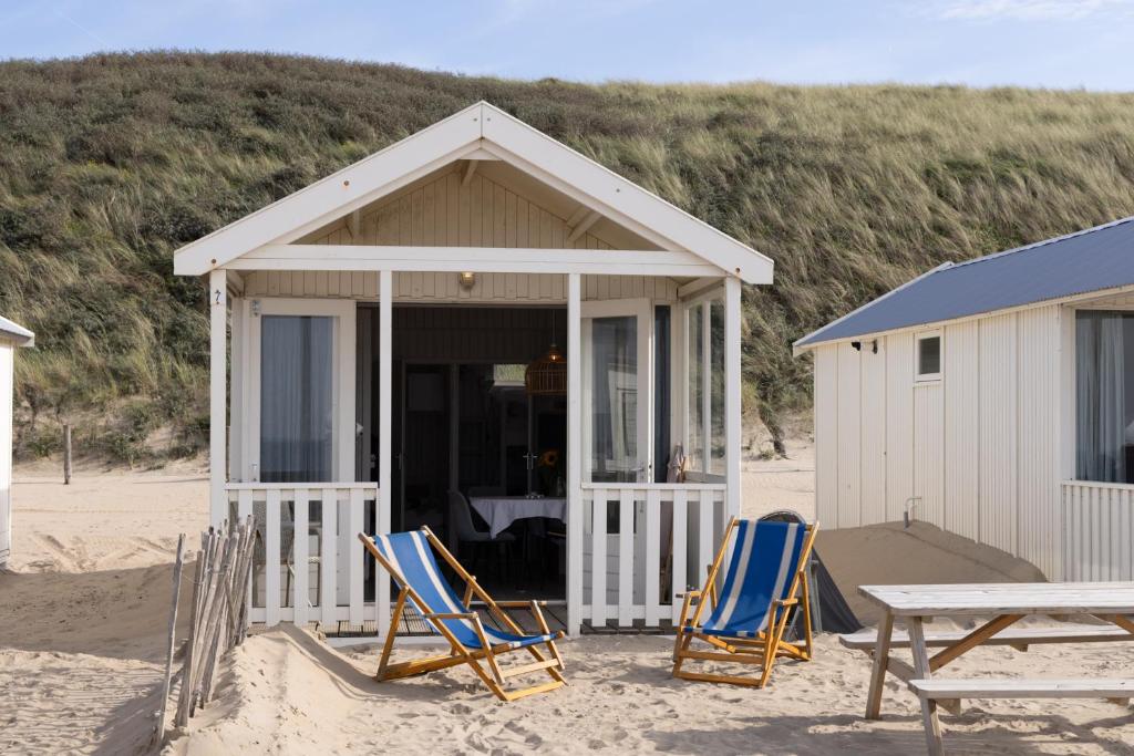 a beach hut with chairs and a table on the beach at Willy Zuid in Katwijk aan Zee