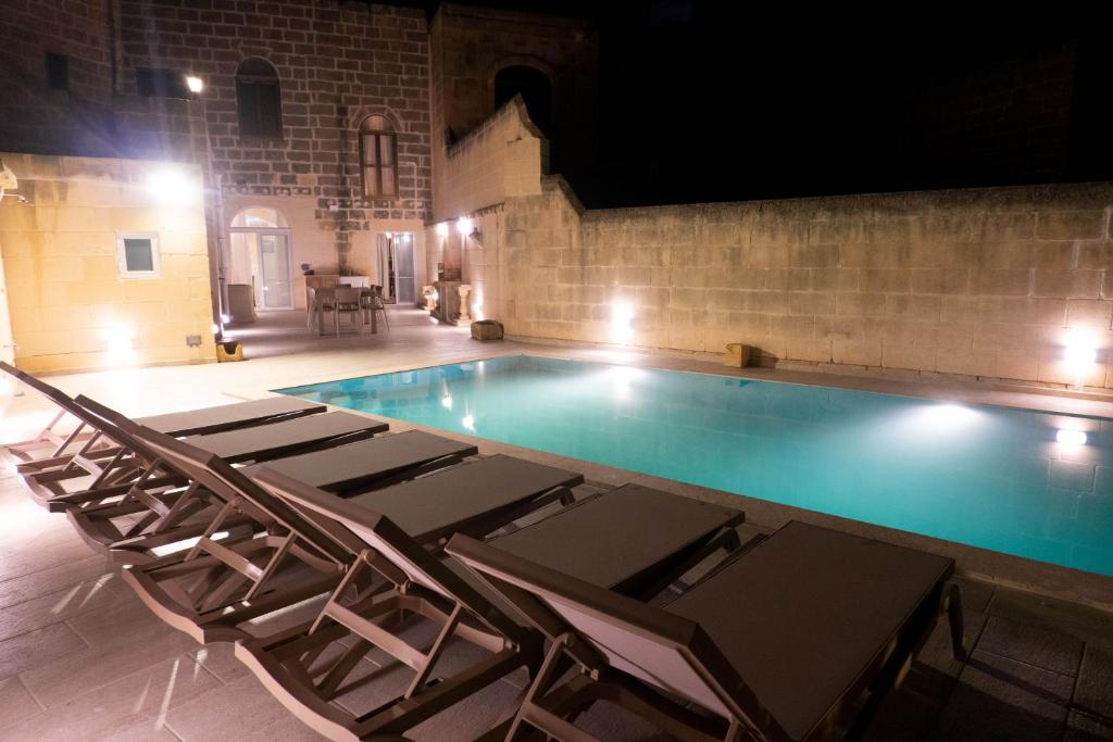 a swimming pool with chairs in a building at SurWig Vacation Townhouse in Kerċem