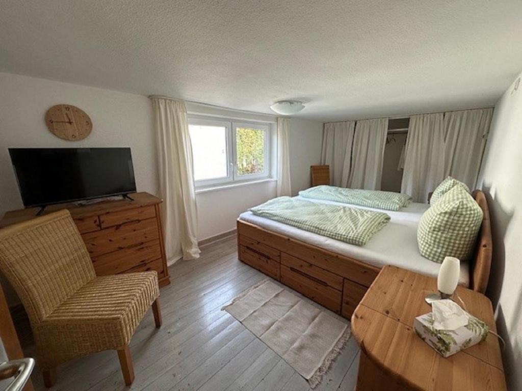 Schlafzimmer mit einem Bett, einem TV und einem Stuhl in der Unterkunft Ferienhaus Konze in Hilchenbach