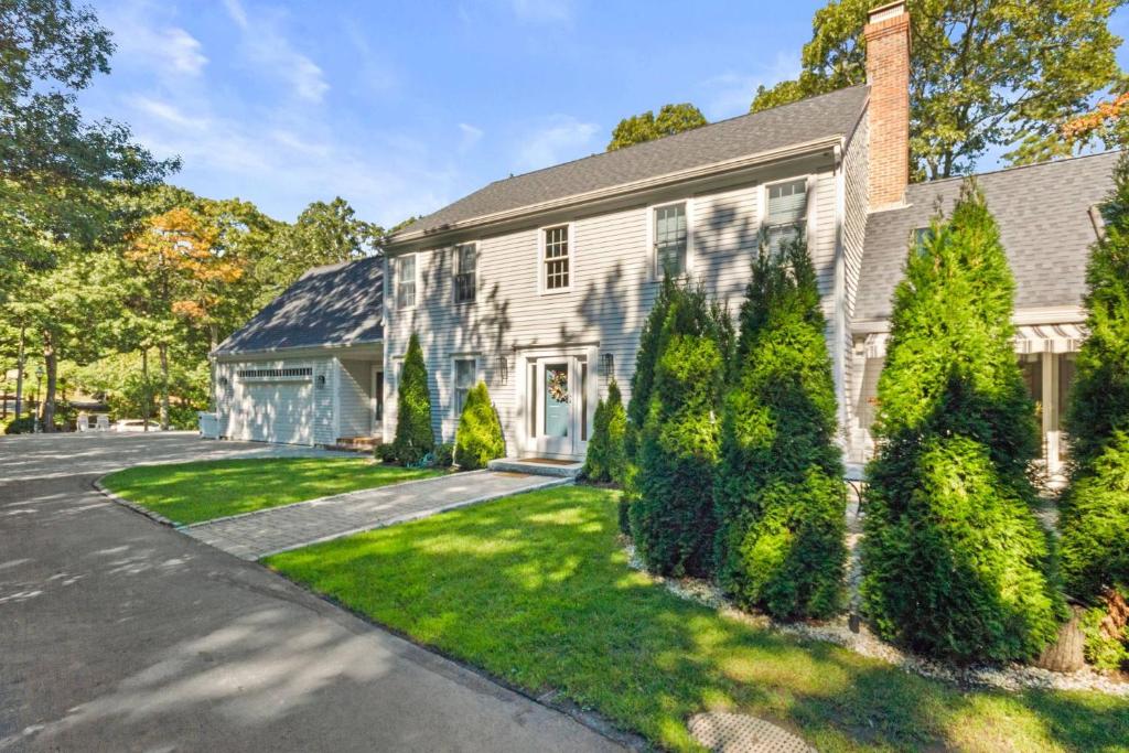 a white house with a driveway and trees at Barnstable Luxury Family Retreat with pool, fire pit and beach nearby in Barnstable