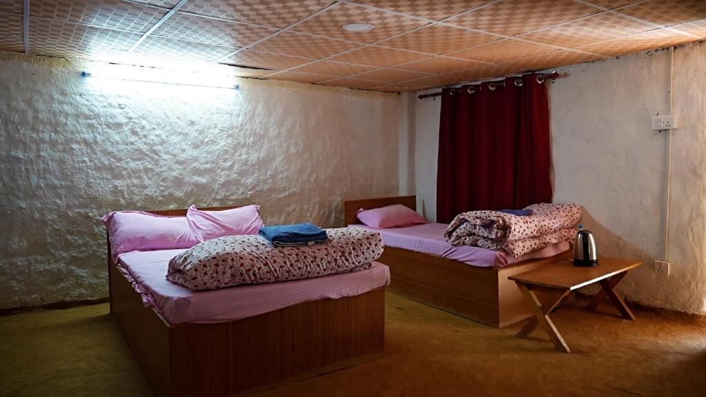 Mahānkāl的住宿－Sindhu Organic Agro And Farmstay，一间设有两张床和一张桌子的房间