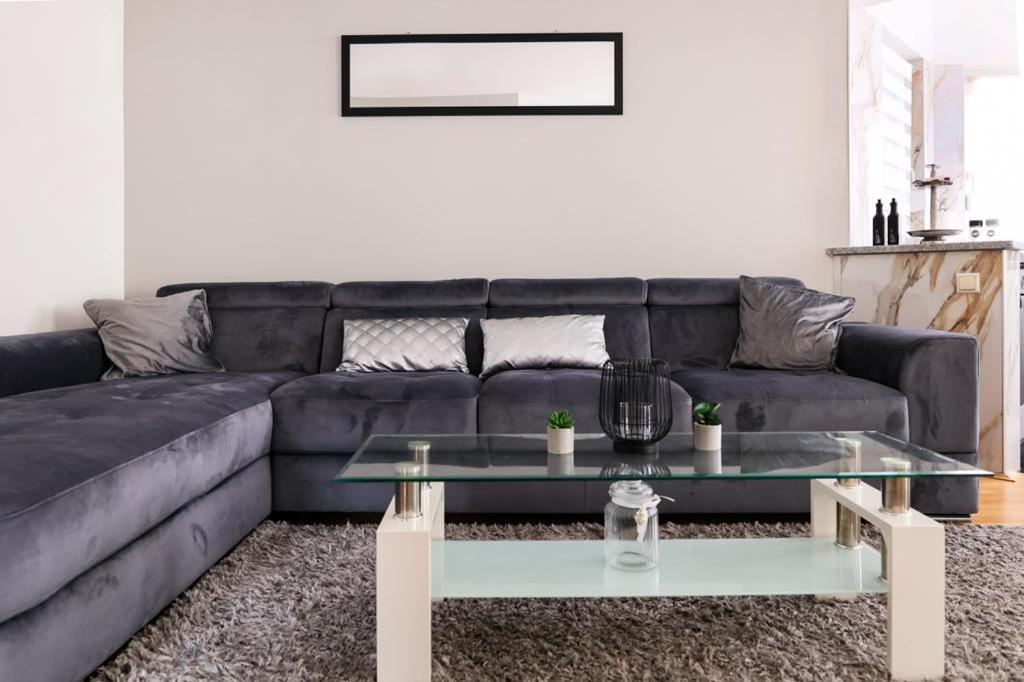 ein Wohnzimmer mit einem schwarzen Sofa und einem Couchtisch in der Unterkunft Apartman Laguna in Zagreb