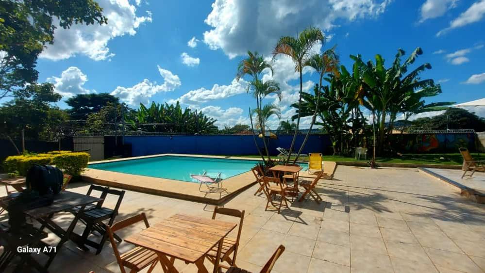 un patio con mesas y sillas junto a una piscina en Das Marias Hostel, en Lagoa Santa