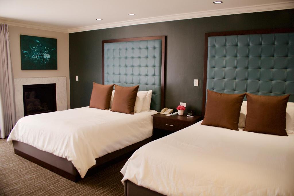 a hotel room with two beds and a fireplace at Munras Inn in Monterey