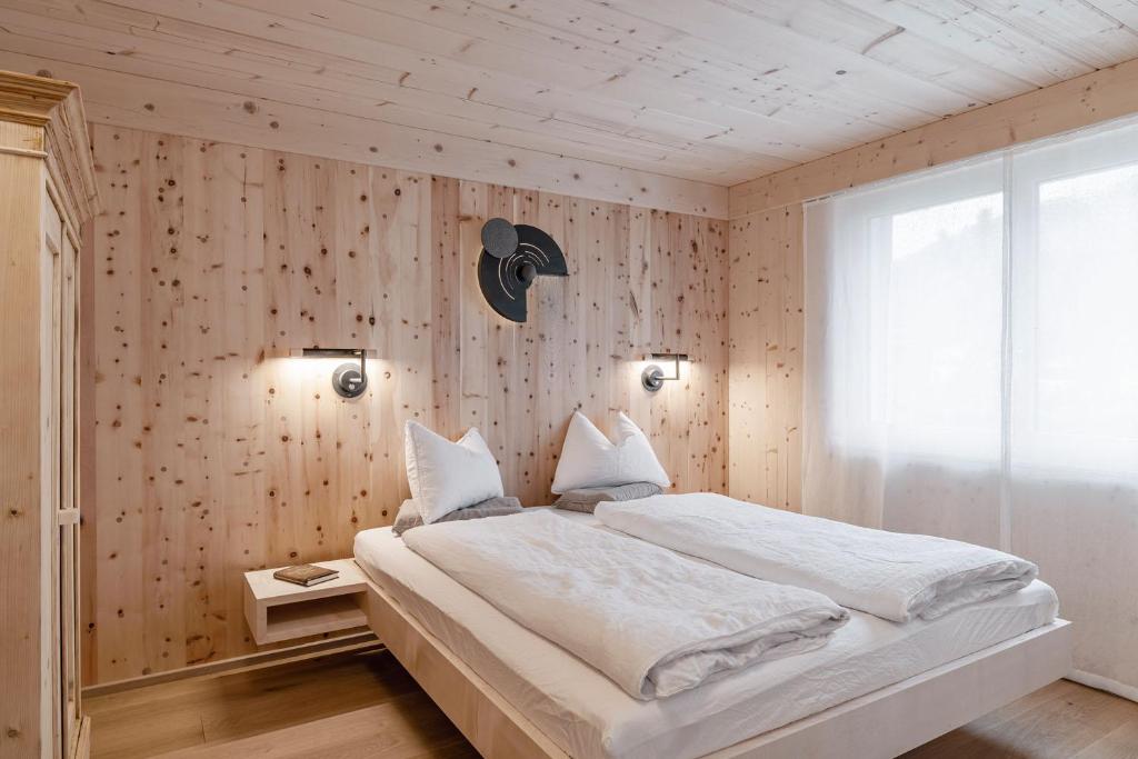 a bedroom with a large white bed and wooden walls at Ferienwohnung Waldzauber Erleben 