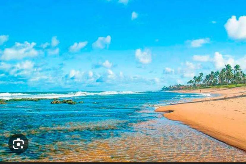een strand met de oceaan en een blauwe lucht bij Suítes Vilas do atlântico a 100M da praia in Lauro de Freitas