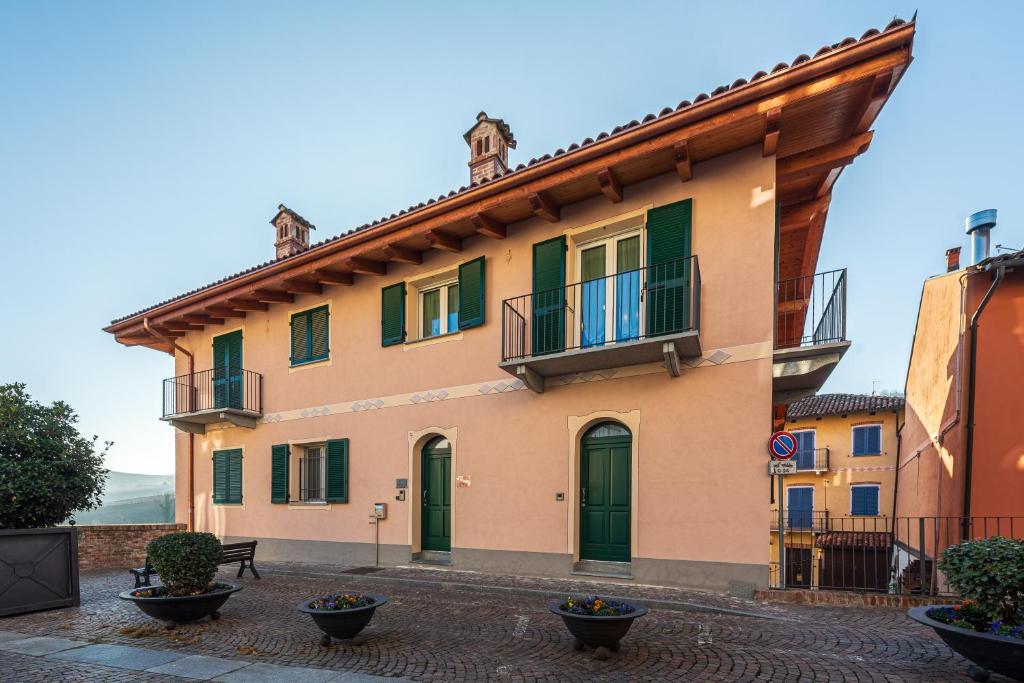 ein Gebäude mit grünen Türen und einem Balkon in der Unterkunft In Piazzetta holiday apartments, Barolo in Barolo