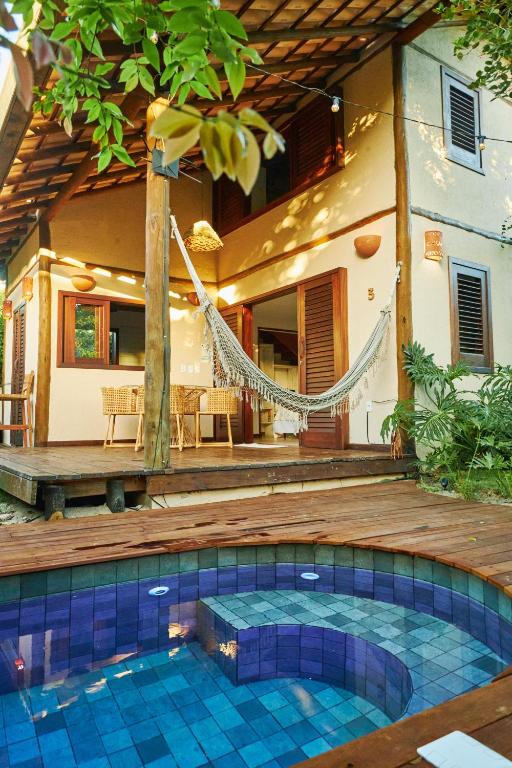 a swimming pool with a hammock in front of a house at Vila Nativa Caraíva in Caraíva