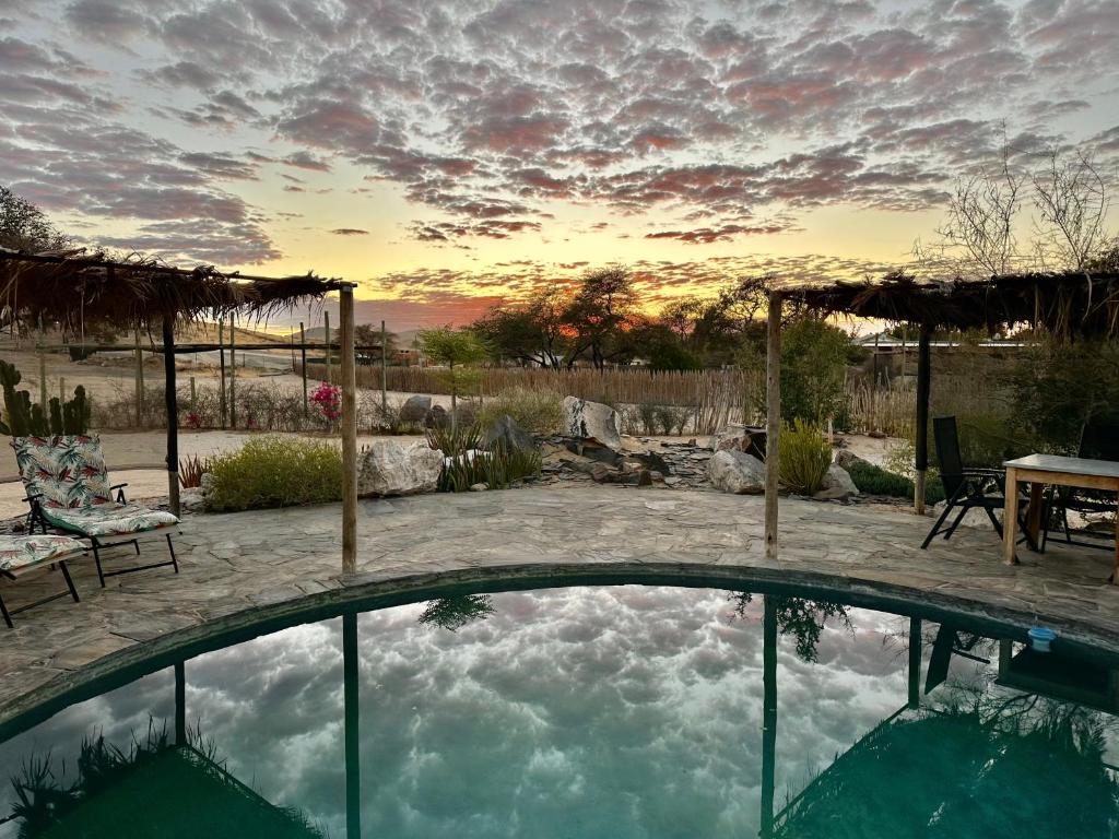 a swimming pool in a yard with a sunset at Daureb Isib Campsite and B&B in Uis