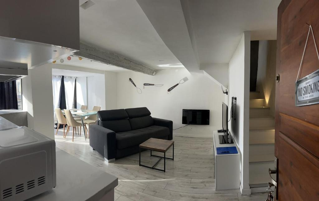 ein Wohnzimmer mit einem schwarzen Sofa und einem Tisch in der Unterkunft Charmante maison Climatisé avec Netflix et Disney plus in Touet-de-lʼEscarène